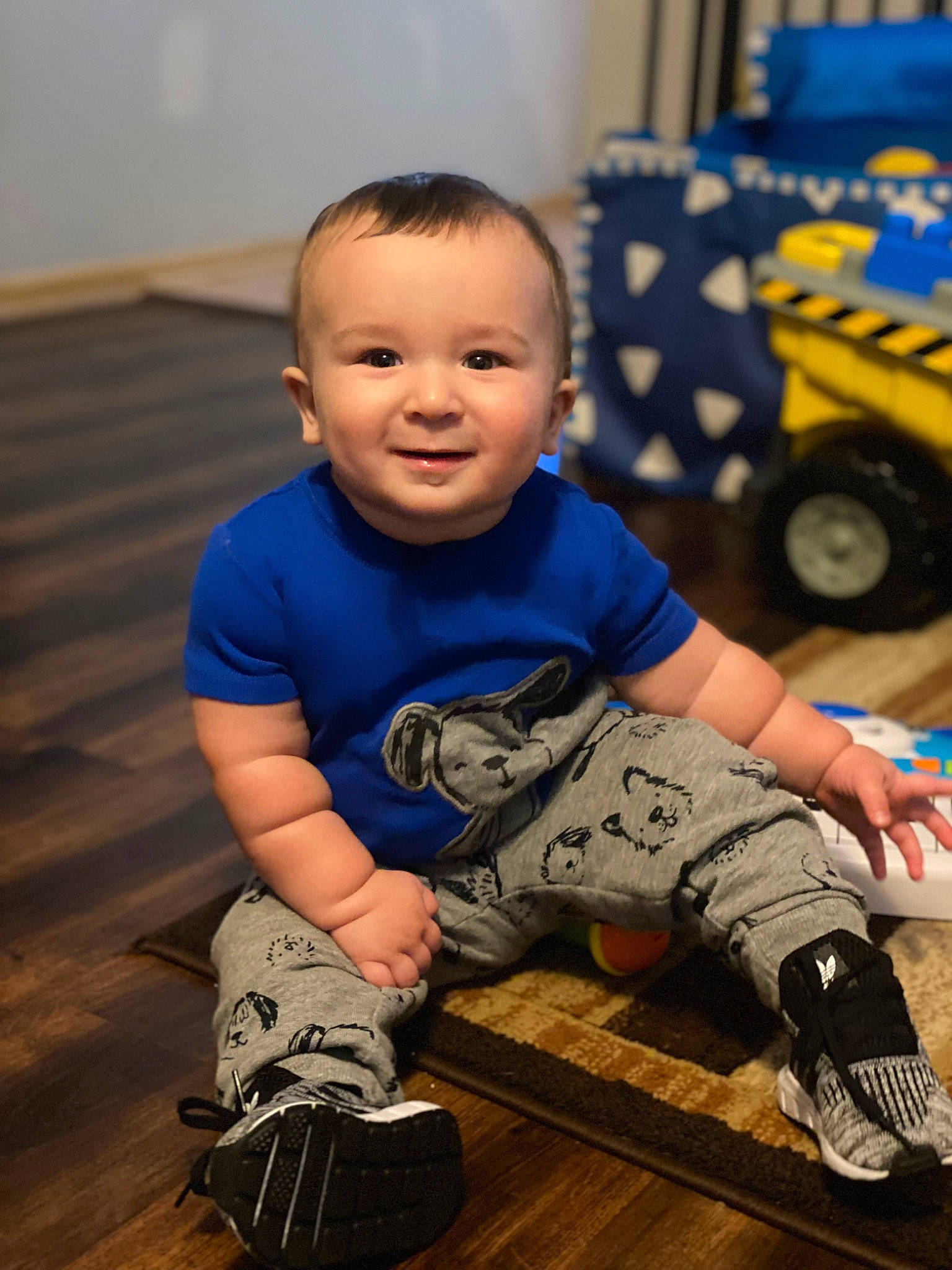 Maaz is registered to the contest to win money with this photo: baby, baby_toddler_clothing, child, electric_blue, flooring, fun, happy, hardwood, human_leg, joy, outdoor_shoe, person, skin, sleeve, smile, standing, t_shirt, tire, toddler, truck
