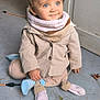 toddler, child, blue_eyes, curly_hair, scarf, beige_jacket, socks, floor, bicycle, indoor, concrete, wall, sitting, smile, cute, curious, clothing, person, portrait, baby