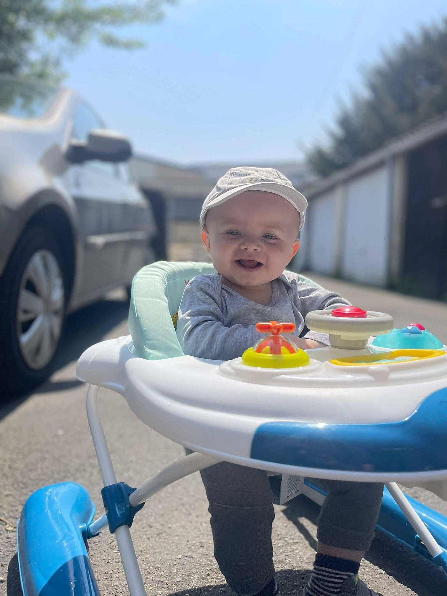Tom a rejoint le concours — aidez-le/la à gagner de superbes lots ! automotive_wheel_system, baby, blue, car, chair, child, fun, grass, happy, headwear, leisure, person, personal_protective_equipment, recreation, sitting, sky, smile, tire, toddler, tree