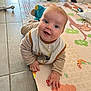 baby, child, play_mat, bib, floor, tile_floor, indoor, happy, smiling, crawling, person, clothing, toy, furniture, legs, colorful, animal_print, alphabet, hand, face