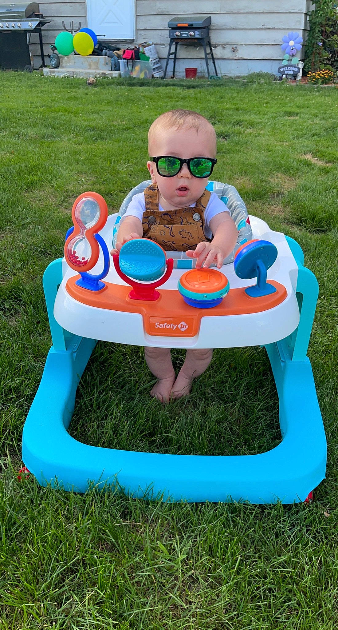 Liam is registered to the contest to win money with this photo: child, city, eyewear, fun, garden, goggles, grass, green, leisure, outdoor_furniture, person, plant, plastic, play, playground, recreation, shorts, sitting, smile, sunglasses