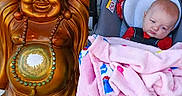 Margaret Hamilton is registered to the contest to win money with this photo: baby, blanket, brick_wall, buddha_statue, car_seat, child, decor, face, golden_statue, hand, indoors, infant, necklace, ornament, pink_blanket, portrait, seated, smiling_statue, tattoo, toy_pattern