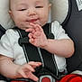 baby, infant, child, car_seat, safety_harness, red_plaid_pants, white_shirt, smile, chubby_cheeks, tiny_hands, buckle, shoe, portrait, closeup, seat_padding, head, eyes, skin, plaid, sleepy