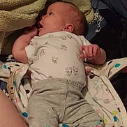Wynter is registered to the contest to win money with this photo: baby, infant, blanket, clothing, onesie, pants, lying_down, soft_texture, curious, skin, face, head, hand, fingers, indoors, fabric, comfort, cute, newborn, child