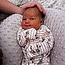 newborn, baby, infant, hand, blanket, onesie, striped_clothing, cartoon_print, soft_texture, resting, cute, sleepy, comfort, gentle_touch, person, indoors, closeup, skin, head, portrait
