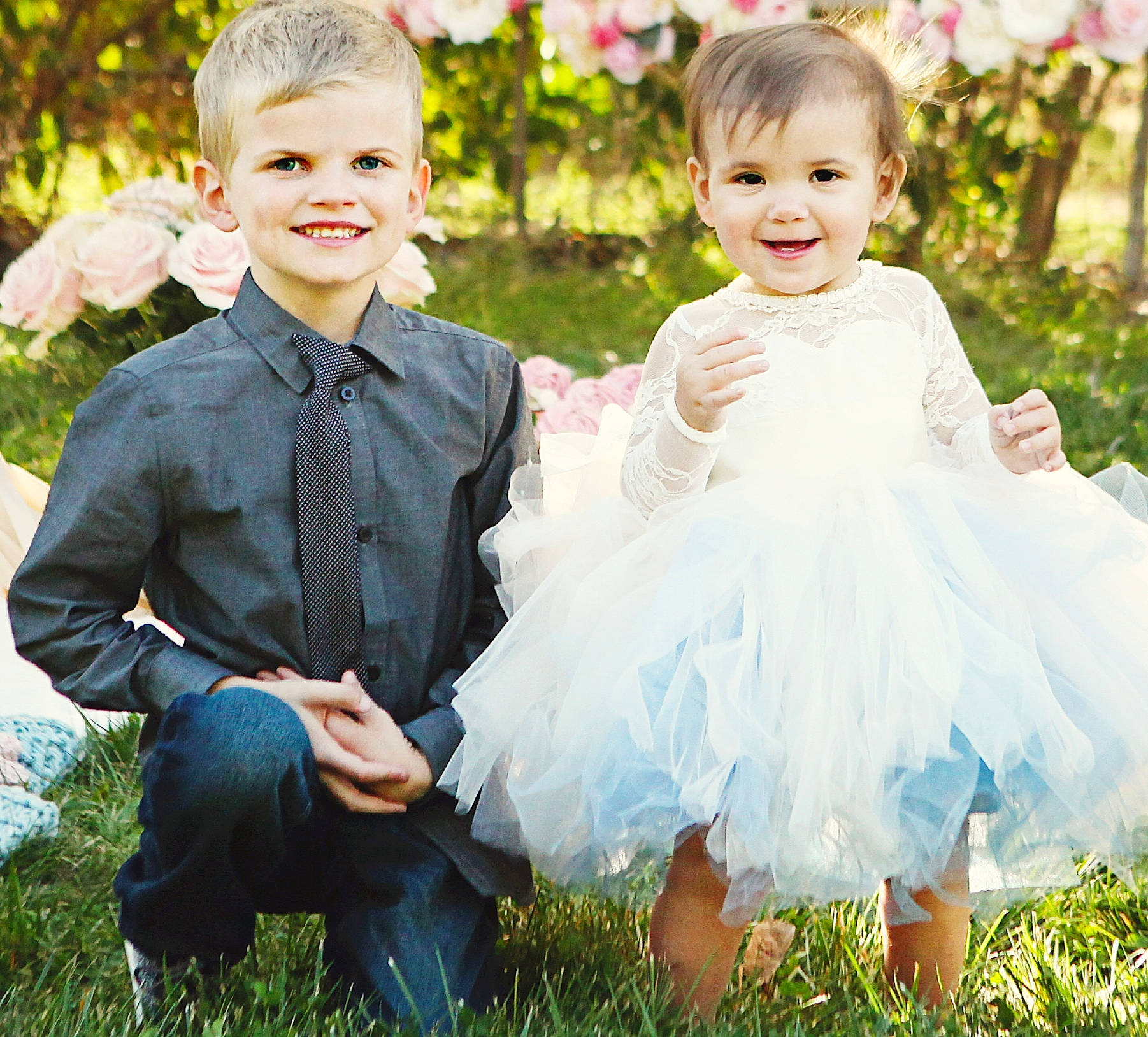 Landon is registered to the contest to win money with this photo: a_line, ceremony, child, clothing, dress, flower_girl, formal_wear, grass, happy, joy, male, outerwear, people, person, photograph, photography, pink, sibling, sleeve, smile