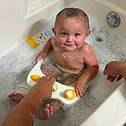 Tucker is registered to the contest to win money with this photo: baby, bathtub, bubble_bath, child, toy, water, foam, smiling, happy, bath_time, skin, hand, playing, infant, person, cute, indoor, cleaning, care, parent