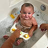baby, bathtub, bubble_bath, child, toy, water, foam, smiling, happy, bath_time, skin, hand, playing, infant, person, cute, indoor, cleaning, care, parent