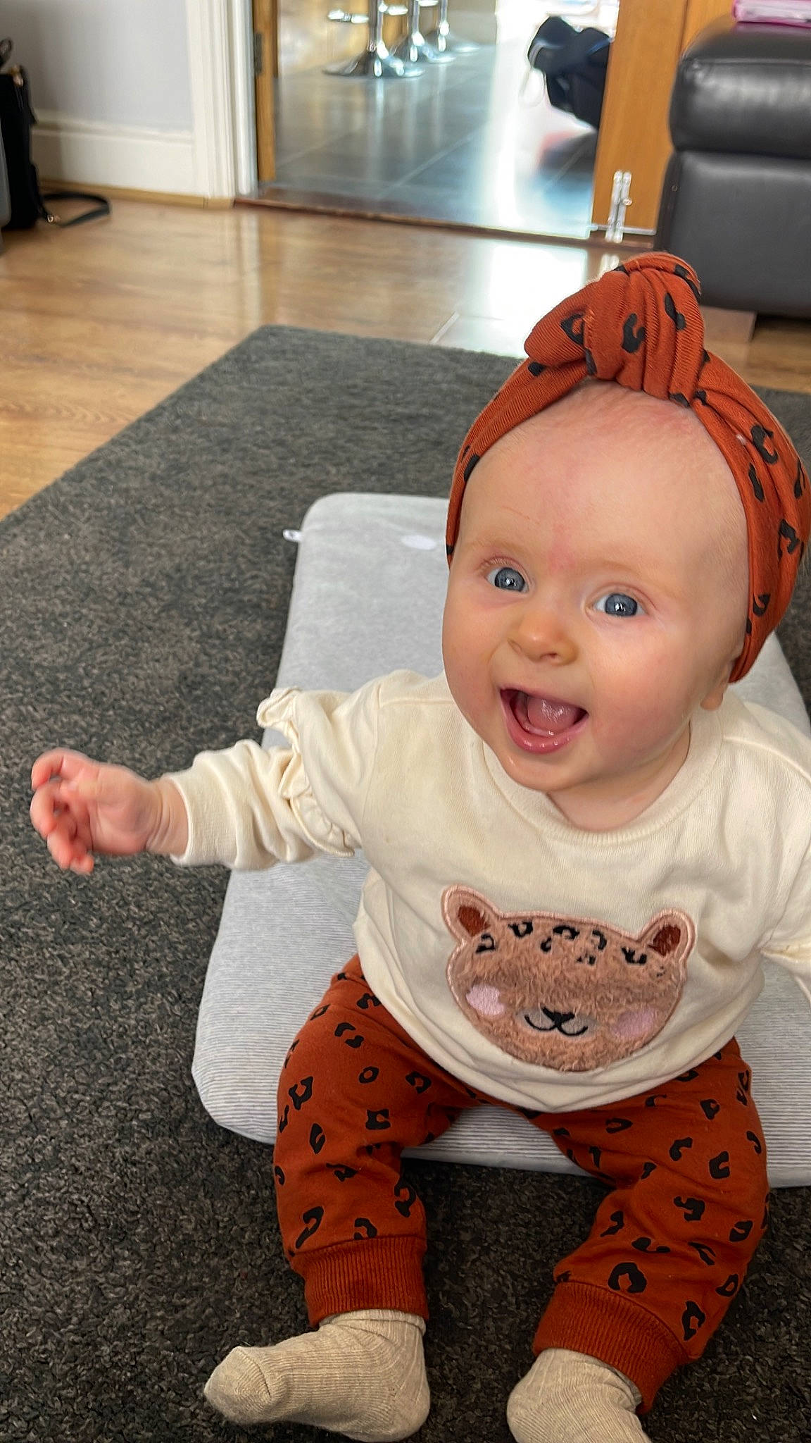 Lacie is registered to the contest to win money with this photo: baby, baby_toddler_clothing, cheek, child, costume_hat, facial_expression, floor, flooring, fun, happy, head, orange, pattern, person, sitting, sleeve, smile, t_shirt, textile, toddler