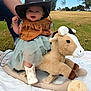 baby, blanket, blue_sky, child, cowboy_hat, cute, fringed_vest, grass, happy, holding_hand, infant, milestone_sign, outdoor, park, person, playful, plush_toy, rocking_horse, smiling, white_boots