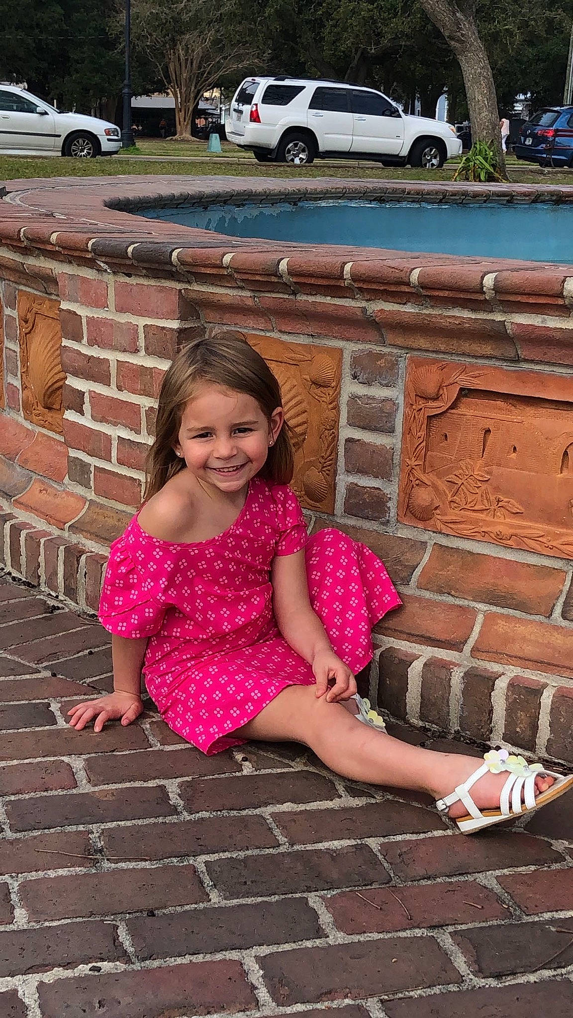 Dalles is registered to the contest to win money with this photo: brick, car, dress, flooring, grass, happy, head, joy, leisure, line, person, photograph, pink, plant, road_surface, sidewalk, smile, thigh, tire, vehicle