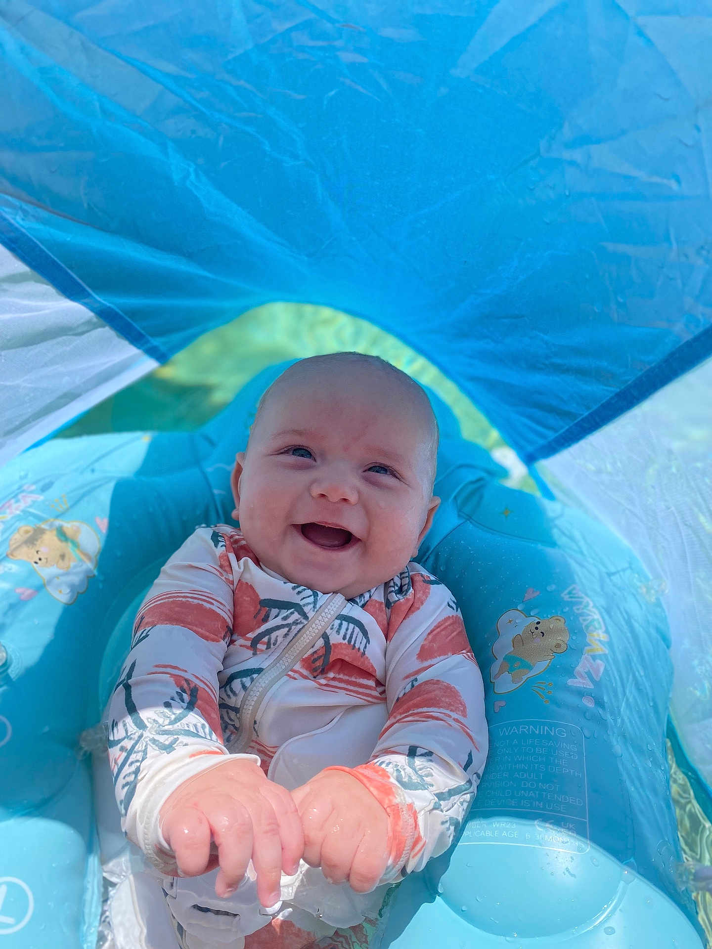 Linkon is registered to the contest to win money with this photo: baby, smiling, water, pool_float, sunshade, swimsuit, infant, outdoor, summer, happy, child, blue, inflatable, sitting, playful, water_toy, cute, sunlight, recreation, joy