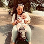 animal_ride, baby, bench, casual_clothing, child, footwear, happy, lake, nature, outdoor, parent, park, playground, seesaw, smiling, sunglasses, sunlight, tattoos, trees, woman