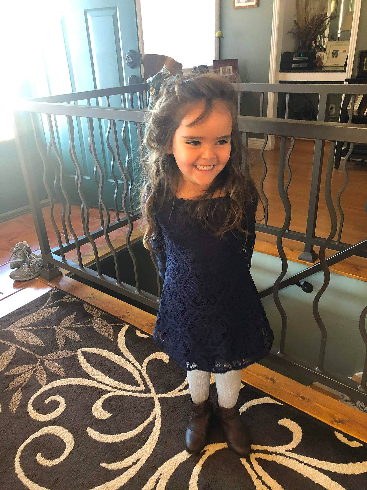 Emma is registered to the contest to win money with this photo: beauty, child, fashion_design, floor, flooring, fun, hairstyle, happy, hardwood, human_body, human_leg, joy, metal, pattern, person, picture_frame, room, sitting, smile, television