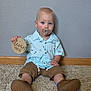 Cayden joined the competition — help win amazing prizes! baby, child, infant, carpet, pacifier, shirt, shorts, wooden_sign, floor, wall, blue_eyes, sitting, indoors, casual_clothing, footwear, cute, person, portrait, holding, light