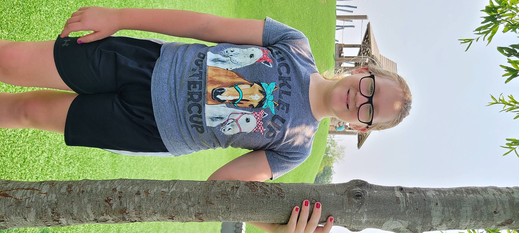 Emma is registered to the contest to win money with this photo: arm, art, cool, elbow, eyewear, gesture, glasses, grass, hand, human_body, joint, joy, neck, person, sleeve, t_shirt, thigh, tree, trunk, vertebrate