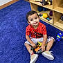 Damian Politz is registered to the contest to win money with this photo: child, boy, smiling, sitting, purple_carpet, toys, dinosaur_toys, wooden_shelf, playroom, indoor, casual_clothing, shorts, sneakers, happy, cute, young_child, floor, carpet, furniture, playtime