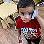 toddler, child, boy, toy_story, red_shirt, phone, indoor, classroom, wooden_floor, small_chairs, table, looking_up, curious, expression, casual_clothing, playing, young_child, person, floor, furniture