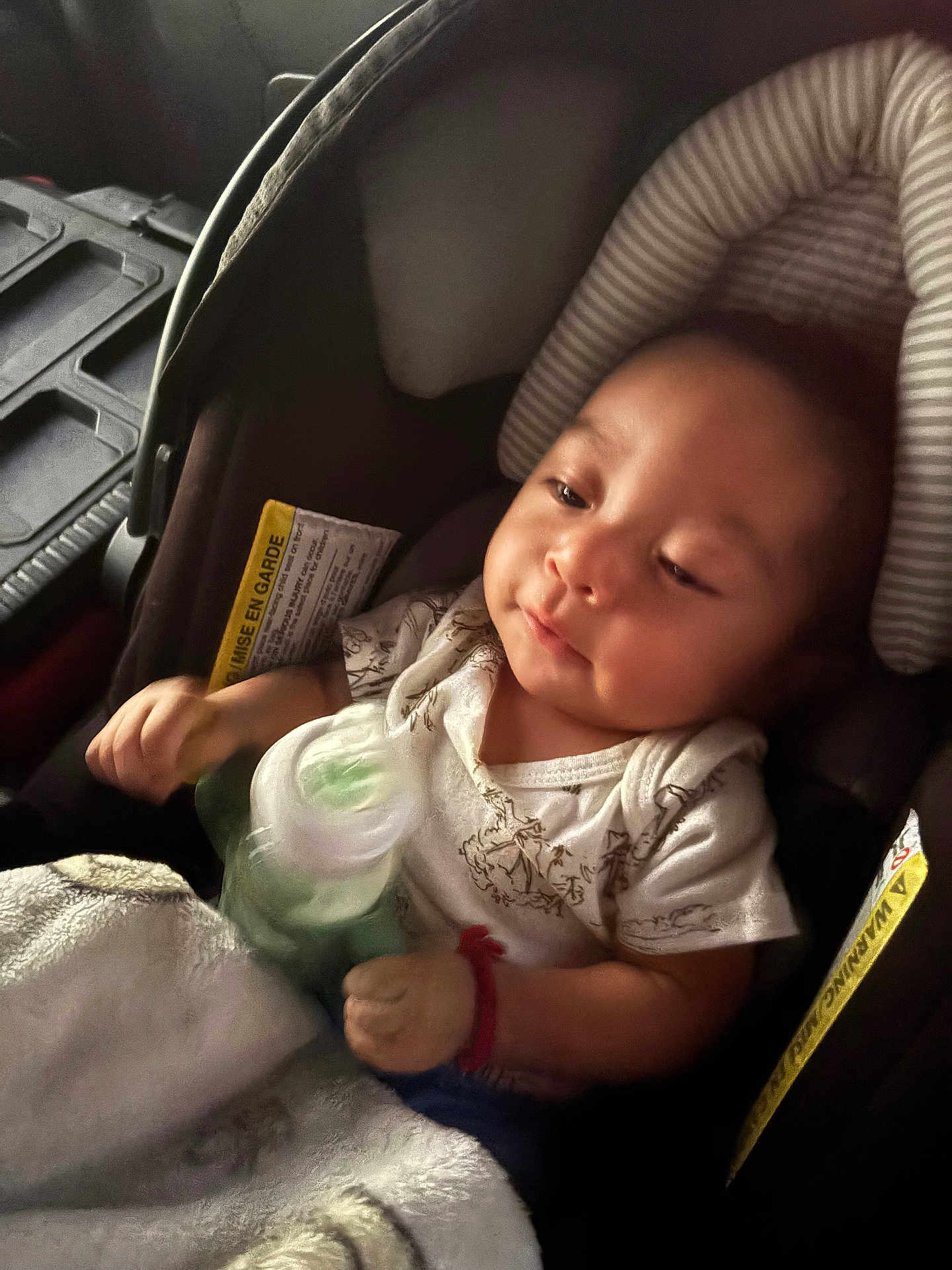 Issac is registered to the contest to win money with this photo: baby, car_seat, bottle, blanket, infant, child, clothing, seat_belt, soft_lighting, indoors, portrait, cute, young_child, person, resting, casual, warm, comfort, relaxed, toddler