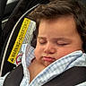 baby, infant, sleeping, car_seat, safety_harness, portrait, face, closed_eyes, peaceful, indoors, vehicle, blanket, blue_clothing, brown_hair, child, passenger, resting, close_up, photography, safe_travel