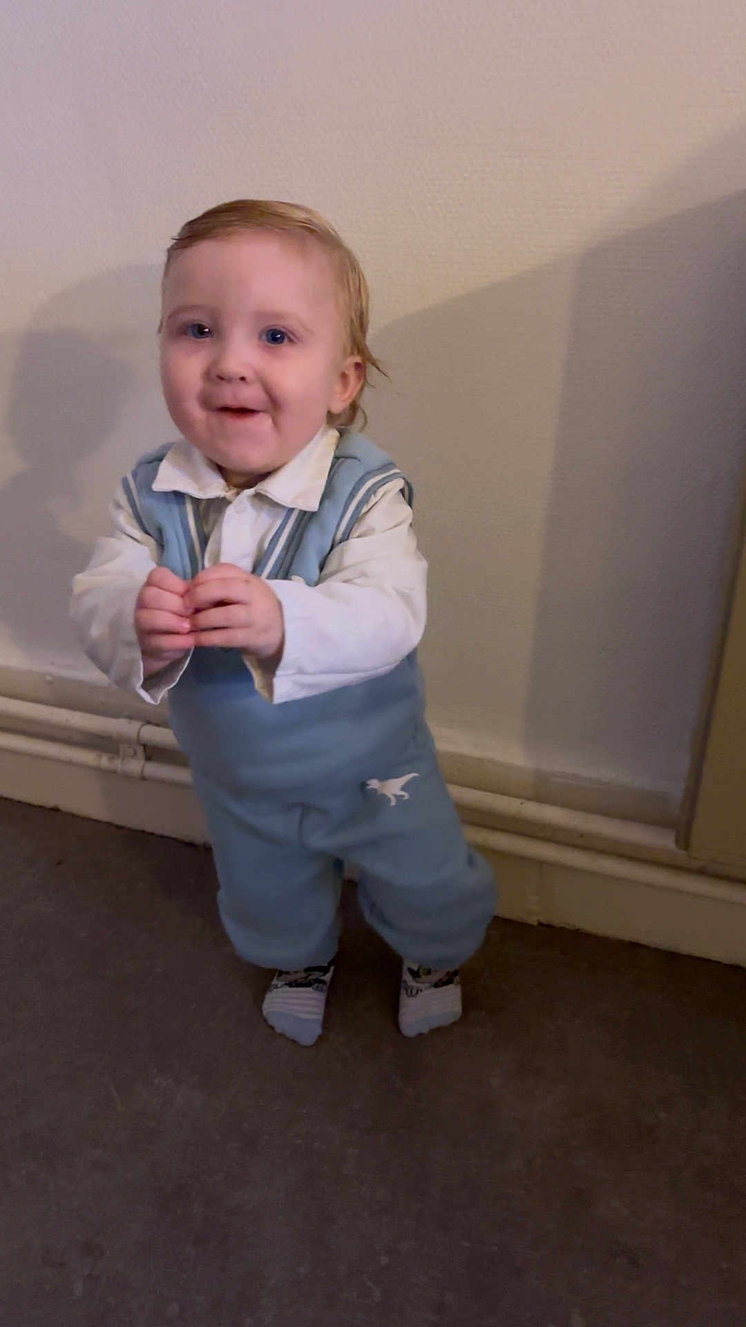 Mayron participe au concours pour gagner de l'argent avec cette photo : toddler, child, indoor, blue_outfit, dinosaur_print, hands, standing, wall, pipes, shadow, floor, socks, cute, happy, person, portrait, young_child, casual_clothing, smile, light