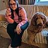 person, dog, glasses, pink_sweater, couch, quilt, window, carpet, drink, straw, indoor, curtain, door, ring, slippers, long_hair, smile, pet, relaxing, home