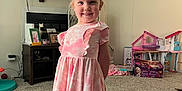 Zoey is registered to the contest to win money with this photo: carpet, cat, child, family_photo, furniture, girl, hair_clip, happy, living_room, painting, photograph, pink_dress, playhouse, shelf, shoes, smile, socks, television, toys, wall_art