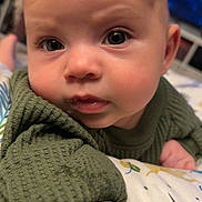 Isla joined the competition — help win amazing prizes! baby, infant, face, eyes, sweater, green_clothing, close_up, indoor, blanket, pattern, curious, skin, head, child, portrait, young, cute, expression, person, toddler