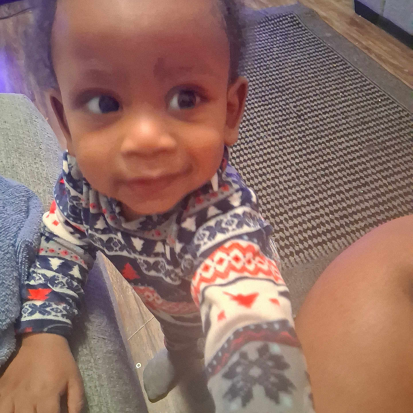 Tylan is registered to the contest to win money with this photo: carpet, child, couch, cozy, curious, cute, floor, footwear, furniture, hand, home, indoor, living_room, pajamas, patterned_clothing, person, smile, toddler, wood_floor, young_child