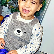 Alex a rejoint le concours — aidez-le/la à gagner de superbes lots ! toddler, child, smiling, overalls, bear_face, toy, purple_toy, sitting, fluffy_rug, christmas_tree, holiday_decorations, festive, indoors, happy, cute, clothing, face, person, celebration, joy