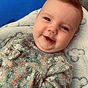 Elèna participe au concours pour gagner de l'argent avec cette photo : baby, blanket, child, chubby_cheeks, closeup, cute, eyes, face, floral_clothing, happy, head, indoor, infant, lying_down, portrait, skin, smiling, soft_texture, warm_clothing, young_child