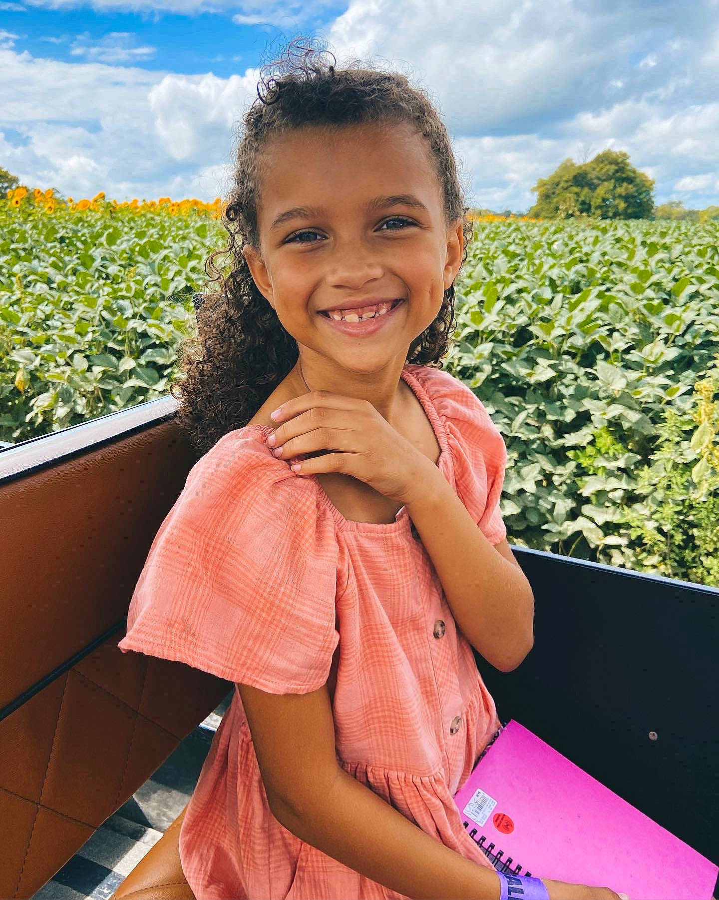 Janiya is registered to the contest to win money with this photo: cloud, facial_expression, finger, fun, grass, hairstyle, happy, joy, leisure, people, people_in_nature, person, plant, recreation, sitting, skin, sky, smile, thumb, toddler