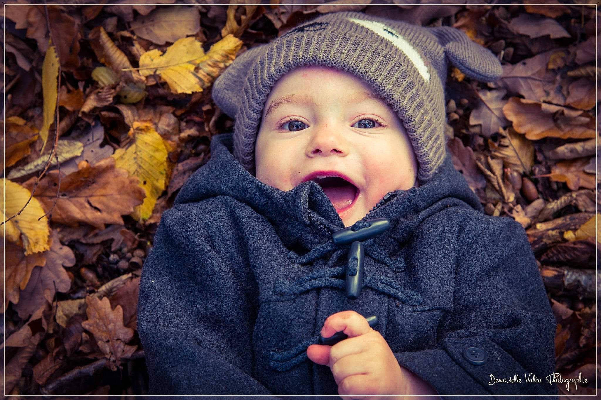 Luciano participe au concours pour gagner de l'argent avec cette photo : autumn, baby, baby_toddler_clothing, beanie, bonnet, cheek, child, deciduous, facial_expression, headwear, hood, iris, knit_cap, knitting, leaf, lip, person, portrait_photography, toddler, winter
