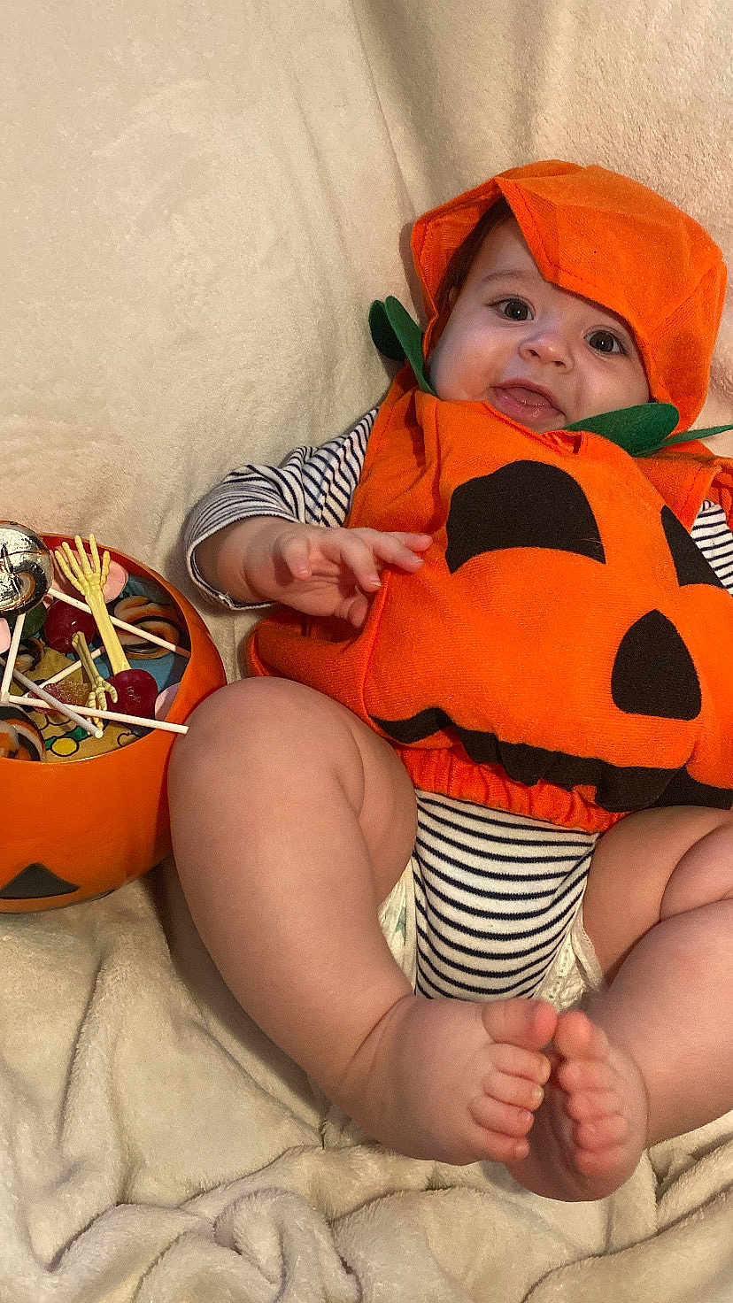Zaïen participe au concours pour gagner de l'argent avec cette photo : baby, blanket, candy, child, costume, cute, feet, festive, halloween, hand, holiday, infant, orange, portrait, pumpkin_costume, skeleton_hand, smiling, soft_texture, striped_clothing, toy