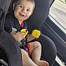 John joined the competition — help win amazing prizes! child, toddler, car, car_seat, safety_belt, seated, smiling, happy, face, portrait, yellow_toys, toy, indoor, vehicle, window, street, daylight, short_hair, barefoot, family