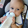 Holden is registered to the contest to win money with this photo: baby, bib, blue_eyes, bottle, car_seat, child, closeup, clothing, cute, feeding, feeding_time, hand, indoor, infant, milk, person, portrait, safety_label, seatbelt, sitting
