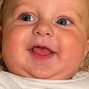 Holden joined the competition — help win amazing prizes! baby, child, face, smile, blue_eyes, white_shirt, text_on_shirt, blanket, close_up, portrait, happy, infant, cute, soft_texture, head, skin, expression, lying_down, indoors, person