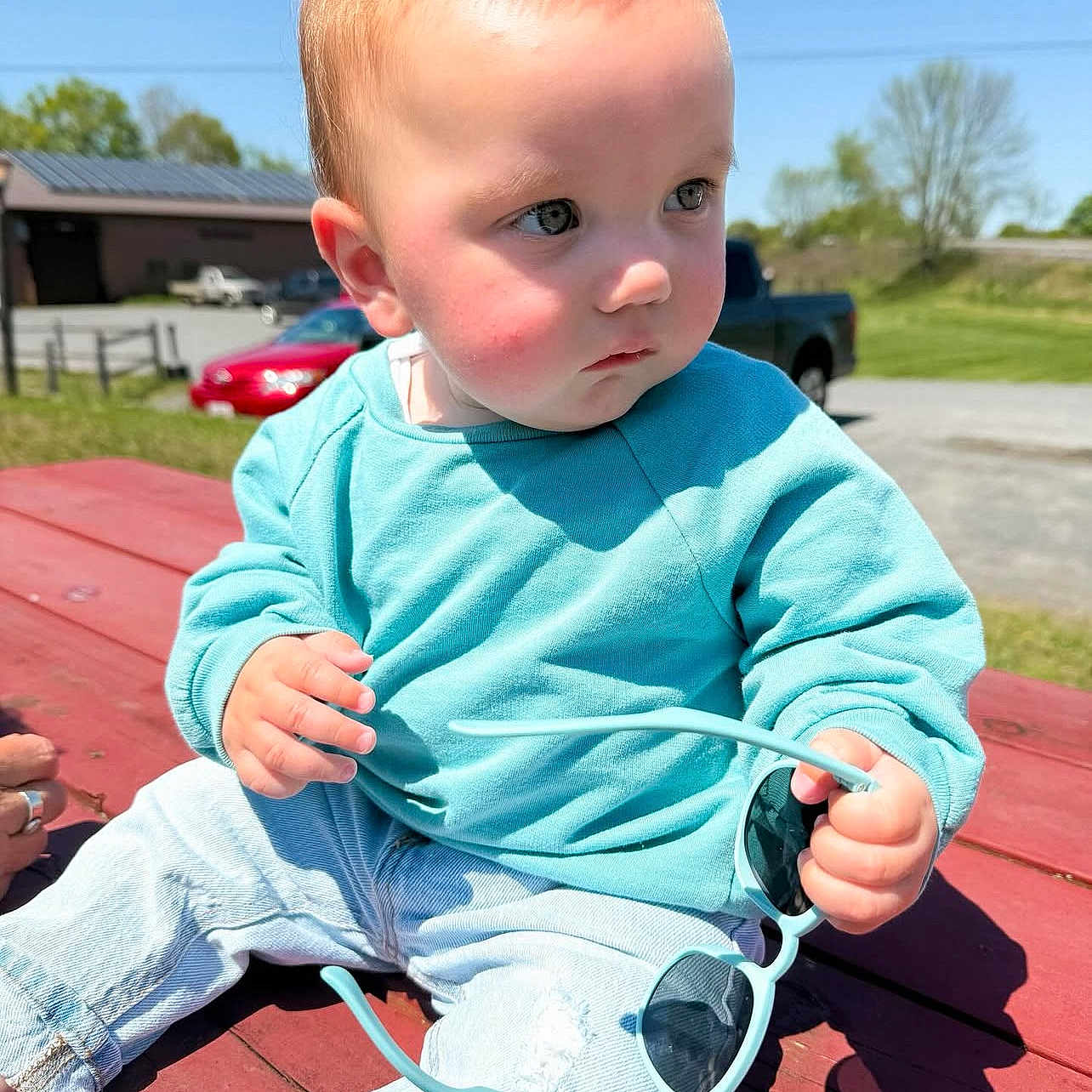 Bennett is registered to the contest to win money with this photo: baby, bench, bodypart, clothing, coat, face, finger, furniture, grass, hand, head, jacket, jeans, outdoors, pants, person, photography, plant, portrait, sitting