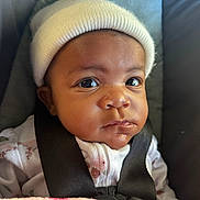 Laelani is registered to the contest to win money with this photo: baby, infant, hat, car_seat, straps, wide_eyes, curious, clothing, child, seatbelt, portrait, indoors, cute, headwear, person, young_child, close_up, expression, face, sitting