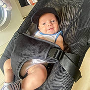 Maël a rejoint le concours — aidez-le/la à gagner de superbes lots ! baby, baby_accessory, baby_clothing, baby_gear, baby_seat, black_cap, domestic, face, floor, happy, home, indoor, infant, laundry, mesh_carrier, person, smiling, striped_socks, washing_machine, white_onesie