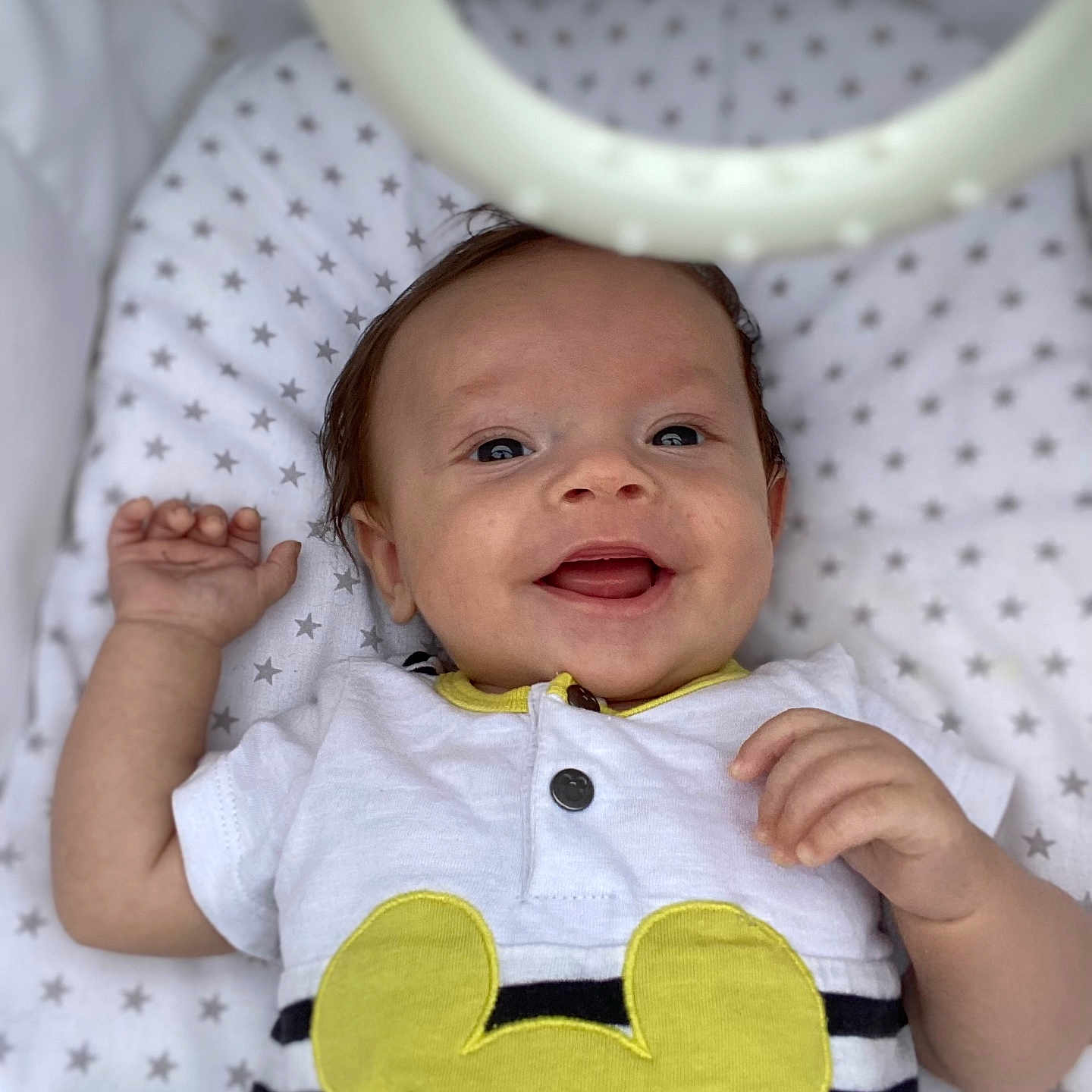Maël participe au concours pour gagner de l'argent avec cette photo : baby, child, closeup, cushion, cute, eyes, face, hand, happy, indoors, infant, lying_down, portrait, smiling, soft_toy, star_pattern, striped_clothing, toy_ring, white_clothing, yellow_mouse_patch