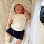 baby, child, comfortable, cushion, cute, indoor, infant, lying_down, navy_shorts, newborn, person, portrait, resting, small_feet, small_hands, smiling, soft_bedding, stars_pattern, striped_socks, white_shirt
