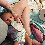 Desian joined the competition — help win amazing prizes! baby, bottle, feeding, infant, tattoo, arm, leg, blanket, pacifier, clothing, person, indoor, comfort, newborn, care, resting, skin, holding, bed, soft