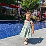 Eleysa a rejoint le concours — aidez-le/la à gagner de superbes lots ! child, girl, dress, blue, yellow, pool, water, outdoor, sunlight, shadow, concrete, umbrella, red, tree, greenery, carousel, chairs, table, summer, playful