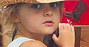 Alexa is registered to the contest to win money with this photo: arm, background, blonde_hair, butterfly, child, closeup, curious, expression, face, hat, indoor, looking, person, portrait, red_background, skin, straw_hat, tank_top, wood, young