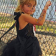 Alexa is registered to the contest to win money with this photo: child, girl, face_paint, temporary_tattoo, black_tutu, fishnet_stockings, outdoor, chain_link_fence, sunlight, trees, playful, posing, costume, summer, daylight, portrait, young, smiling, confident, casual