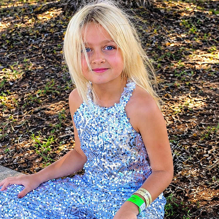Alexa joined the competition — help win amazing prizes! child, girl, portrait, outdoor, park, tree, forest, sequin_dress, blue_dress, blonde_hair, blue_eyes, smiling, sitting, sunlight, nature, leaves, ground, wristbands, fashion, photograph