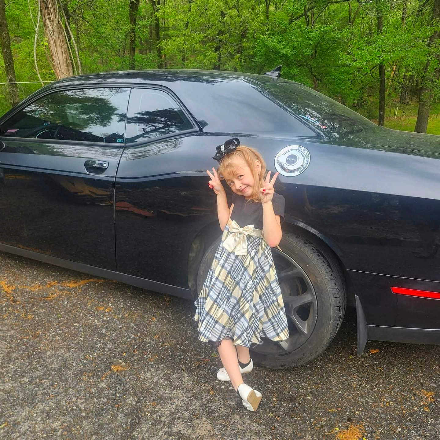 Alexa joined the competition — help win amazing prizes! child, girl, car, black_car, plaid_dress, peace_sign, outdoor, trees, smiling, posing, vehicle, wheel, road, nature, greenery, cute, happy, footwear, accessory, daylight