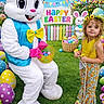Alexa joined the competition — help win amazing prizes! child, easter_bunny, easter_eggs, basket, flower_crown, grass, costume, yellow_top, floral_pants, happy_easter_sign, picket_fence, colorful_eggs, pink_gloves, blue_vest, outdoor, celebration, spring, holiday, festive, smiling
