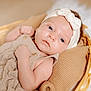 baby, infant, face, headband, bow, basket, pillow, knit, beige, neutral_colors, clothing, cute, portrait, newborn, child, soft_texture, sleepy, indoors, closeup, resting